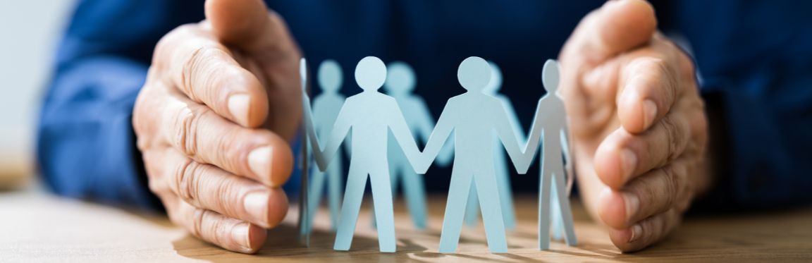 A person's hands holding a paper cutout of a group of people holding hands.