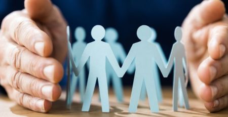 A person's hands holding a paper cutout of a group of people holding hands.