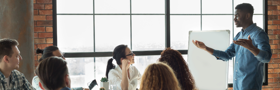 A man enthusiastically presents to a group of people during a corporate meeting.