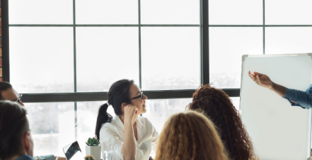 A man enthusiastically presents to a group of people during a corporate meeting.