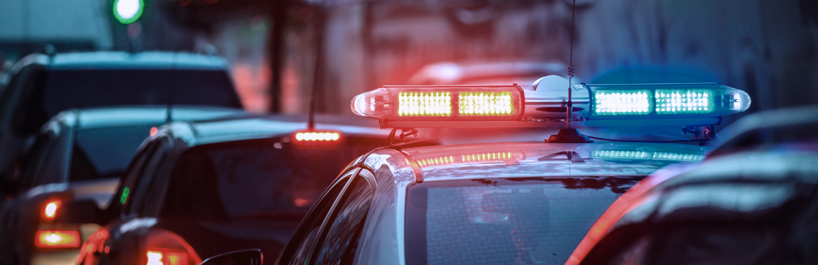 A police siren on top of a police car standing in a line of cars.