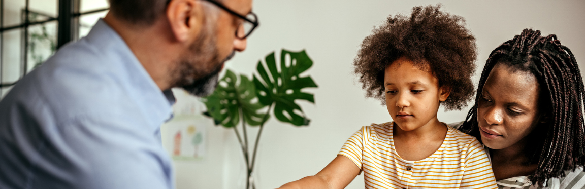 A mother and child sitting down with a practitioner. The mother and child are both facing the practitioner.