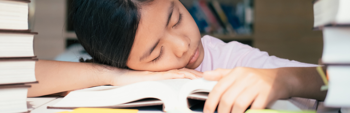 A young girl is asleep on her book.