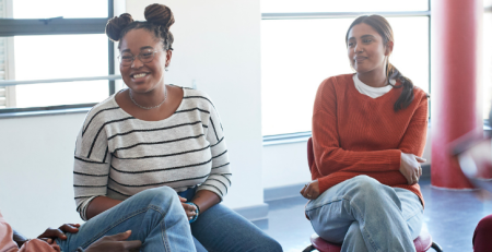 A group of people sit together in a circle, talking and laughing.