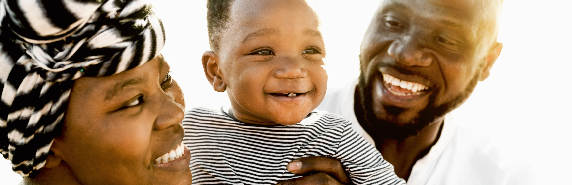 A baby being held up by two smiling parents.