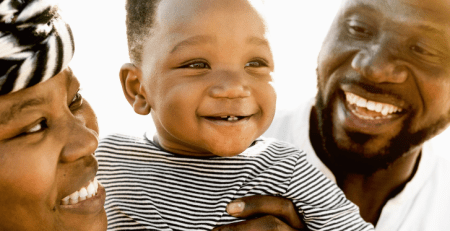 A baby being held up by two smiling parents.