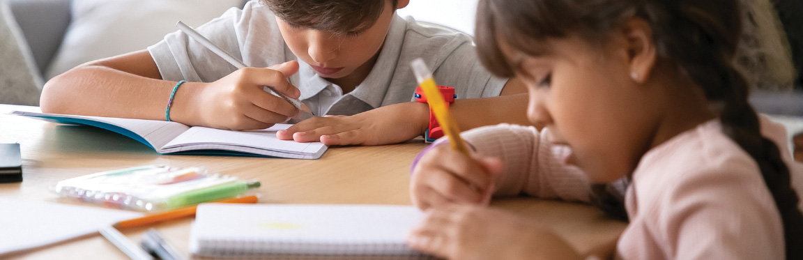 Two young students writing in their notebooks.