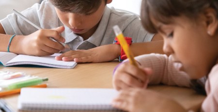 Two young students writing in their notebooks.