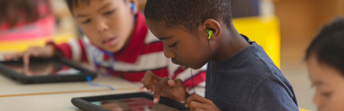 A child has earphones in and is using a tablet device.