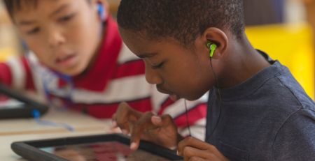 A child has earphones in and is using a tablet device.