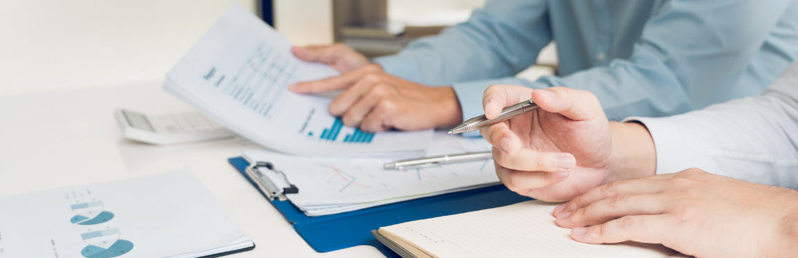 Two people reviewing documents and analyzing sets of data at a table.