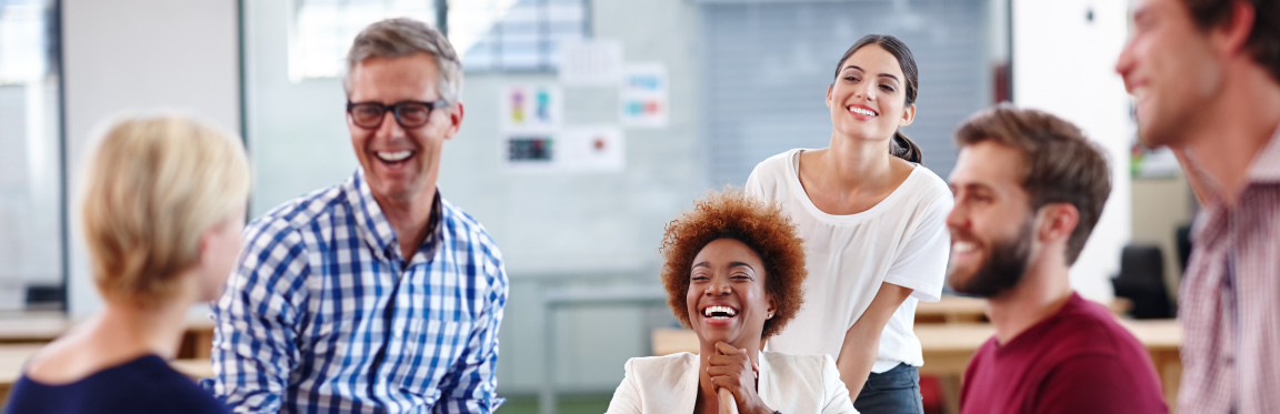 A group of colleagues laughing together in the office.