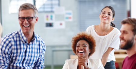 A group of colleagues laughing together in the office.