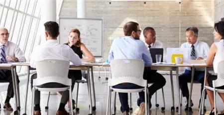 A team of people sitting at a long table in a modern office space.