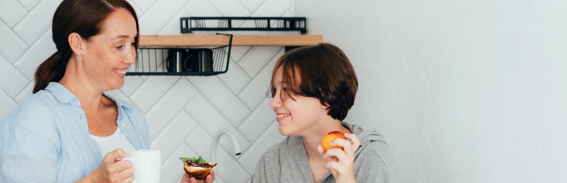 A mother and child hanging out in the kitchen, enjoying a light meal.