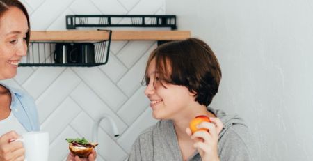 A mother and child hanging out in the kitchen, enjoying a light meal.