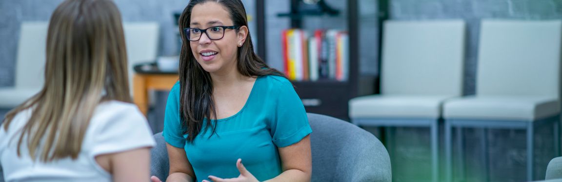 A practitioner explains something to a client who is sitting across from them. They look passionate about what they are sharing with their client.