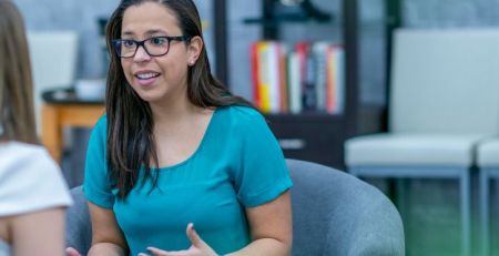 A practitioner explains something to a client who is sitting across from them. They look passionate about what they are sharing with their client.