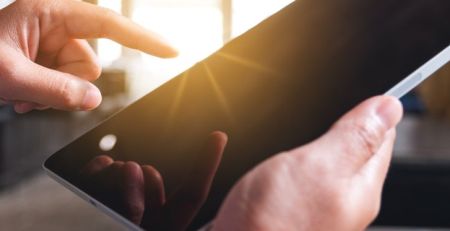 Hands holding an iPad and pointing to the screen.